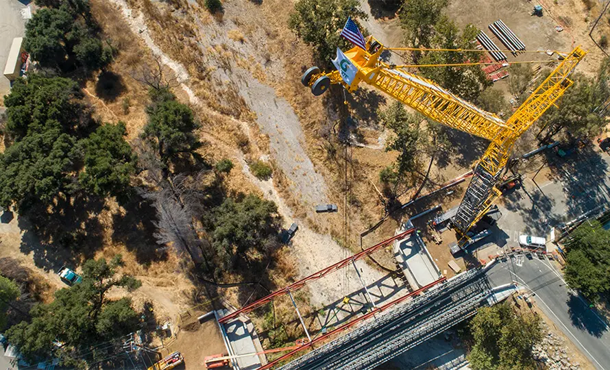 Aerial view of bridge construction site with large crane and steel beams.