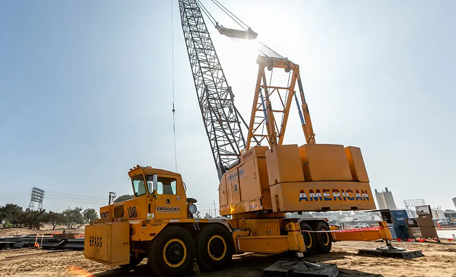Large orange crane at a construction site labeled "American Bragg".
