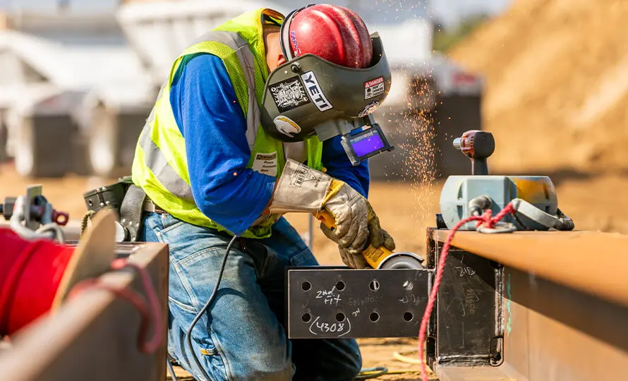 Construction worker grinding steel with sparks flying at a construction site.