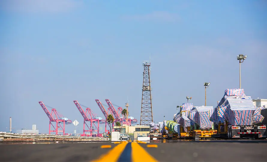 Port with large container cranes and a view down a road leading into the facility.