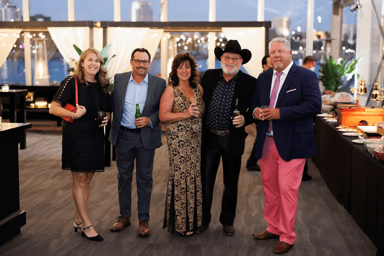 Group of five people posing at an event with soft lighting and decorations.