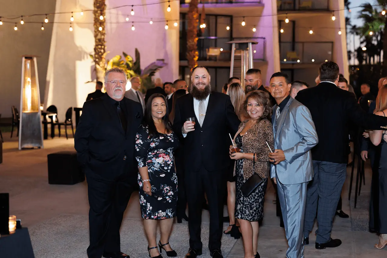 Group of people socializing at an outdoor event with decorative lighting.