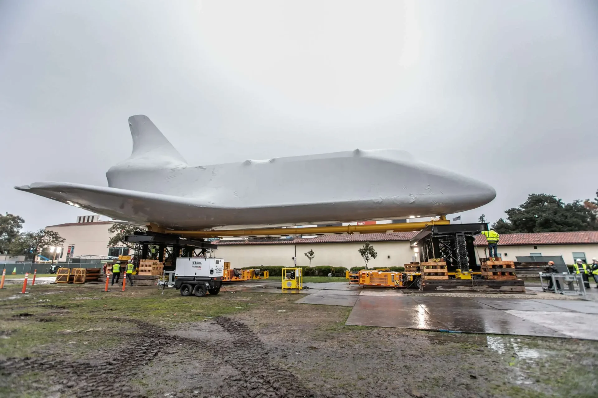 The space shuttle is being carefully lifted into position for launch preparation at the launch pad.