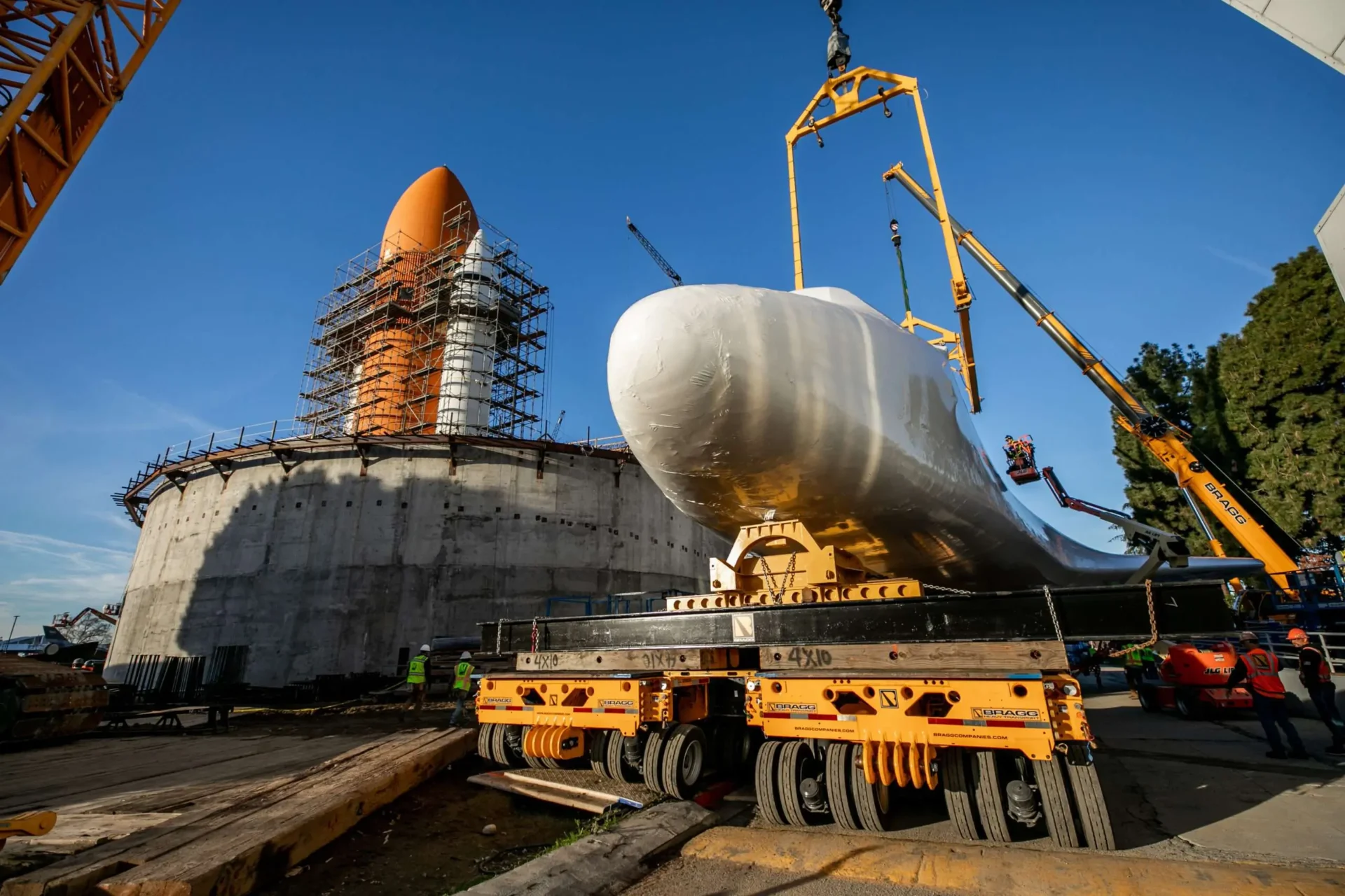 A large white spaceship is being lifted into the air by a crane at a dock, showcasing the lifting process.