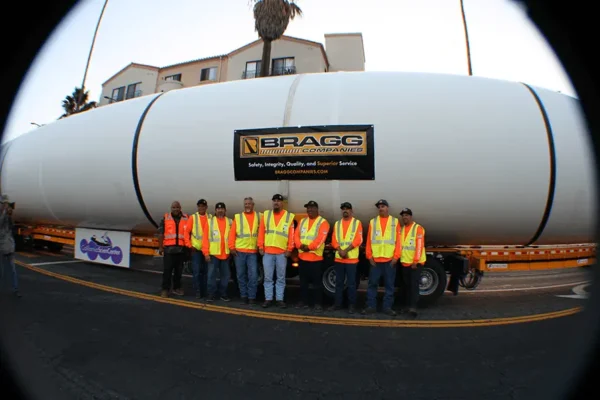 A diverse group of individuals gathered in front of a large truck, showcasing camaraderie and teamwork.