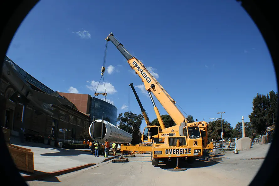 A crane hoists a large object from the top of a building, showcasing construction and heavy lifting in action.