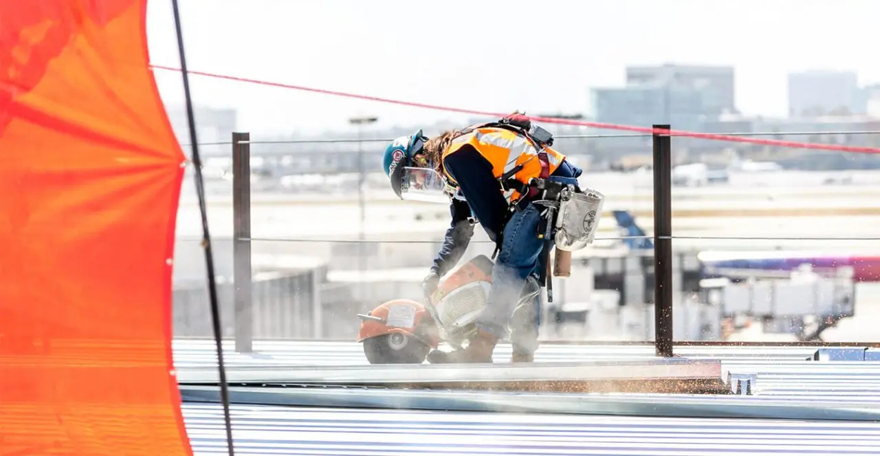 Construction worker using a grinding tool on a bridge deck.
