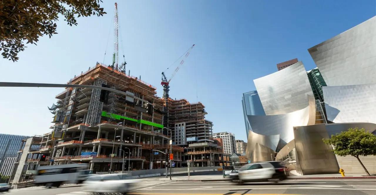 High-rise construction site with steel framework, next to the Walt Disney Concert Hall in a city setting.
