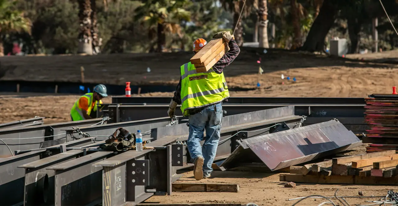 Construction worker moving steel beams on a construction site.