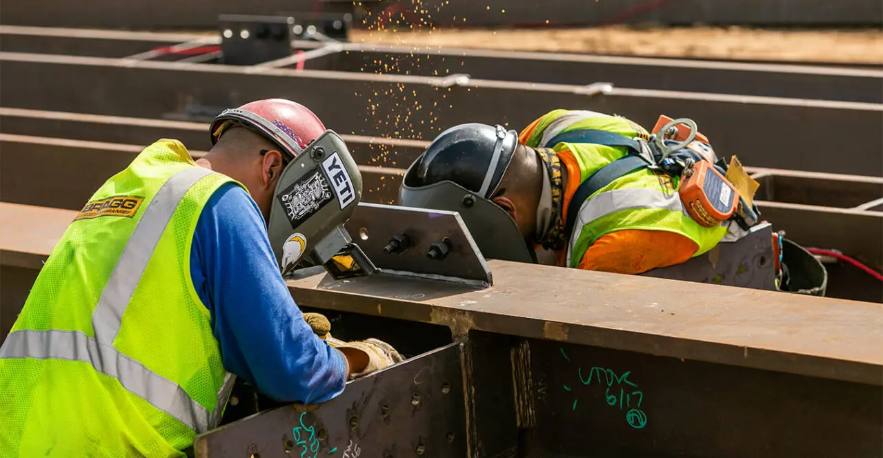 Construction worker welding a steel beam on a construction site.