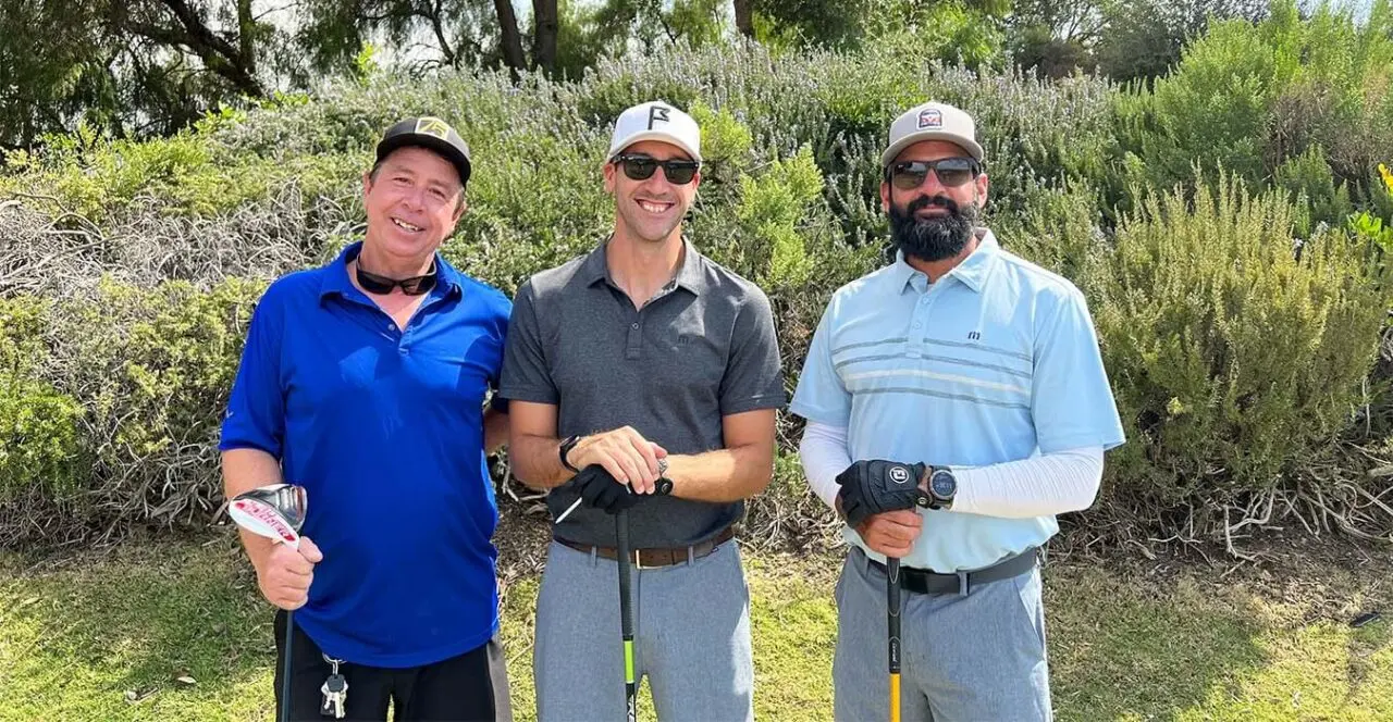 Three golfers posing on a golf course fairway.
