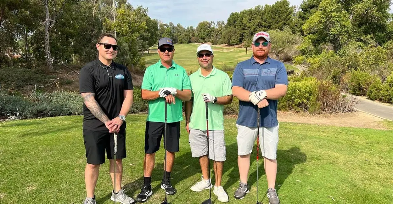Four golfers posing on a golf course fairway.