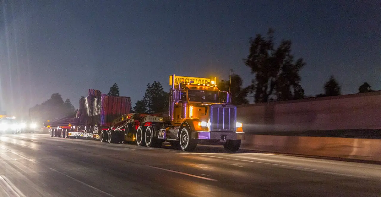 Heavy haul truck transporting an oversized load at night on a highway.