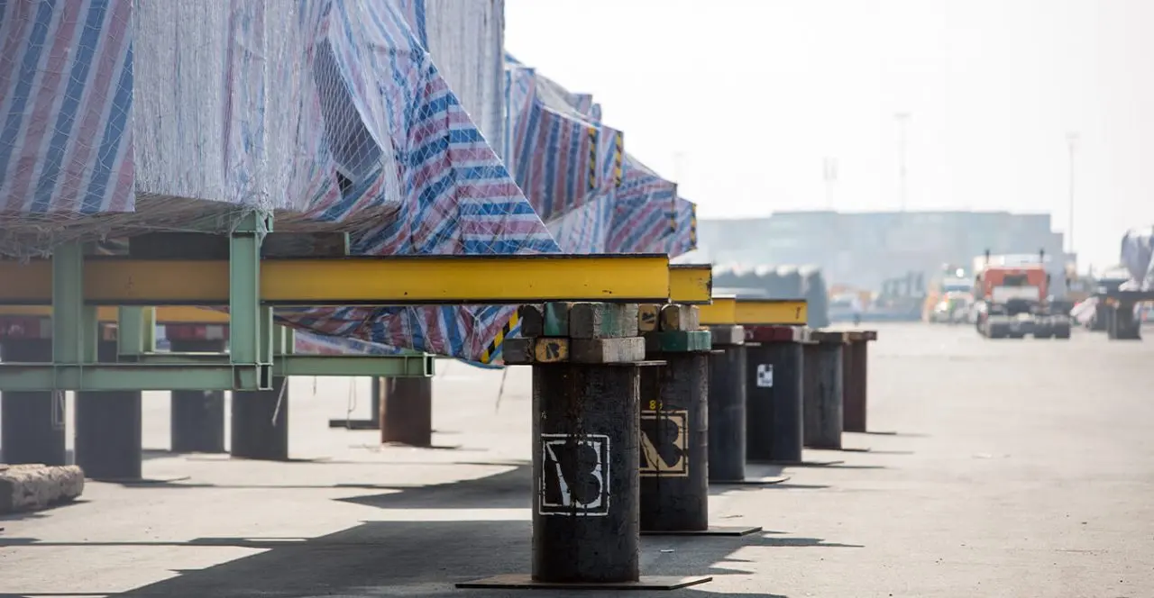 Large industrial component supported on stands in a port or industrial yard.