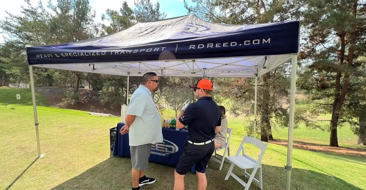 RD Reed booth at a golf tournament sponsorship event, showcasing heavy & specialized transport services.