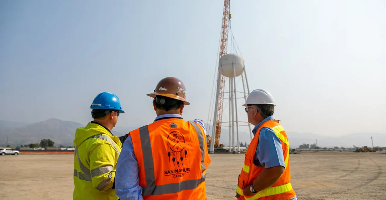 Construction supervisors discussing work near a rising water tower.