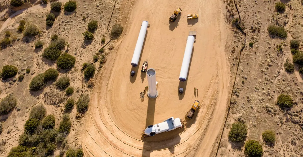 Aerial view of wind turbine tower sections being assembled on a construction site.